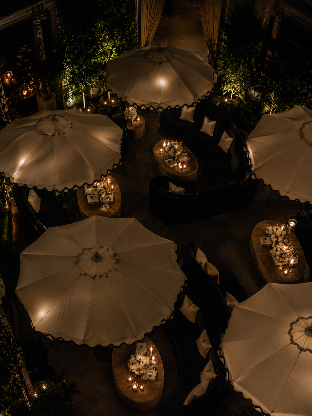 Ivory and black scalloped market umbrellas installed above a luxury lounge in candlelit atmosphere