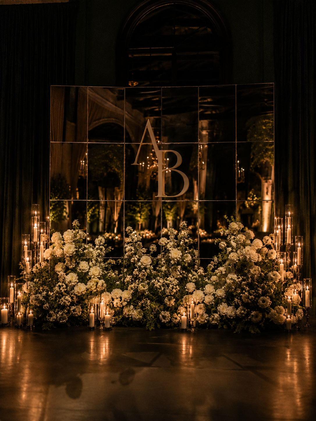 Ceremony mirror cladding backdrop with gold monogram and white floral ground installation